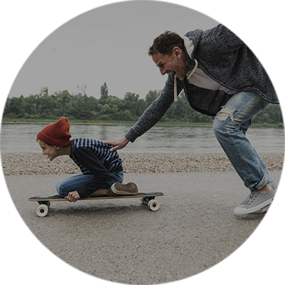 Vater schiebt Kind auf Skateboard an