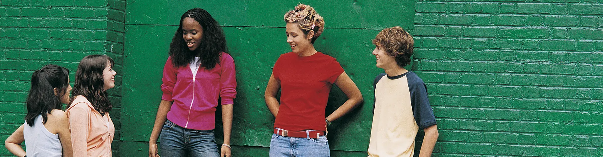 Jugendliche lehnen an Wand und unterhalten sich